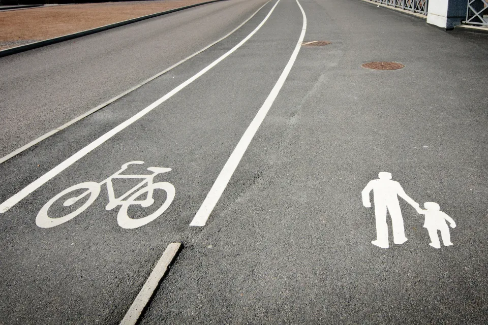 Bike land and pedestrian lane marked with white paint on grey asphalt